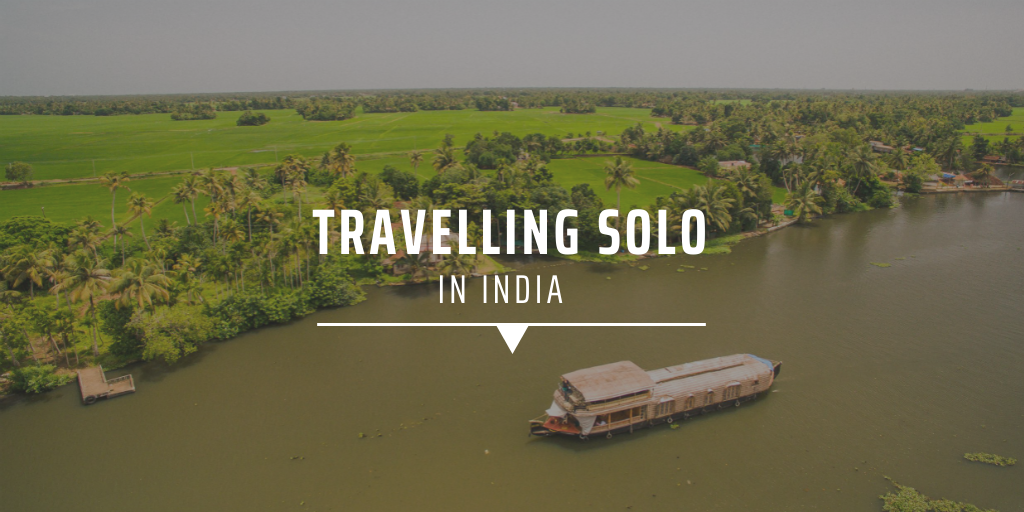A traditional Indian boat sailing on a broad river alongside an island